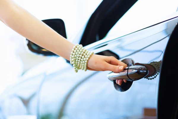 woman's hand opening a vehicle handle in car showroom
