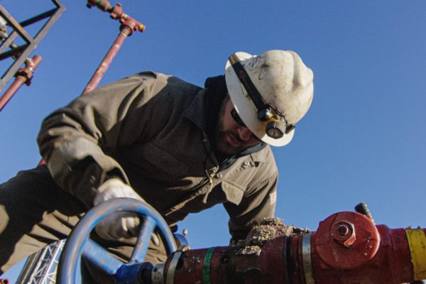 oil and gas employee working on large pipe
