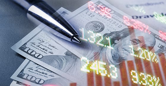 fading picture of dollar bills, pens, and stock numbers