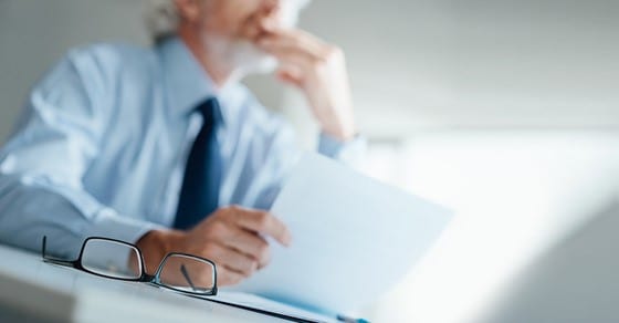 Man reading paper with glasses on the desk