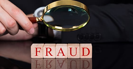 Businessman Examining Fraud Blocks Through Magnifying Glass