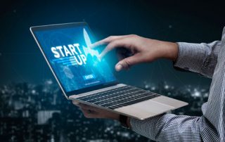 business man holding laptop with words business startup on the screen