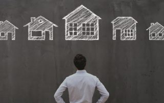 man staring at chalkboard drawing of multiple houses